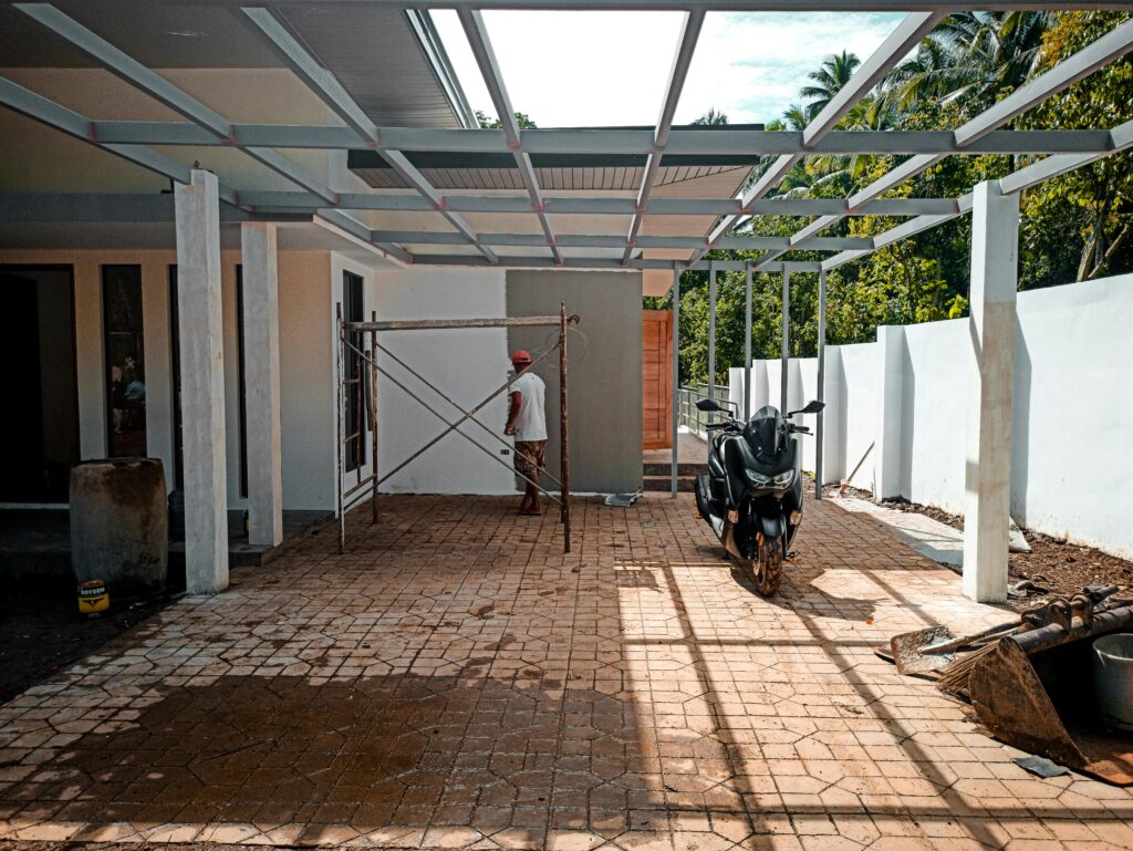 A partially constructed building with scaffolding and parked motor scooter on a sunny day.